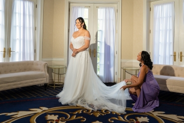 Bride with bridesmaid holding up dress