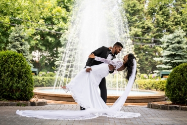 groom bending bride backwards in front of fountain