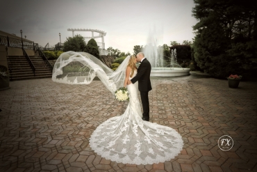 groom kissing bride with elegant veil and long dress