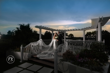newlyweds posing on pergola at night