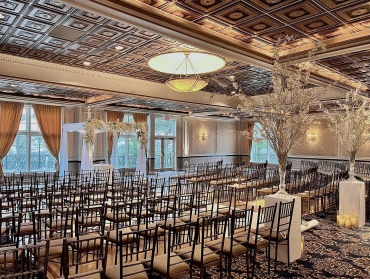 Indoor ceremony setup with chairs and tall flowers