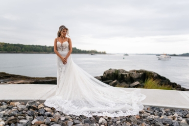 bride with beautiful long dress posing along waterfront walkway