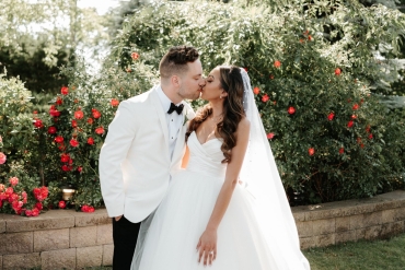 bride and groom kissing in front of garden
